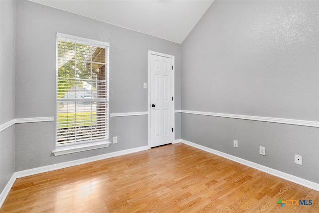 unfurnished room with vaulted ceiling and hardwood / wood-style flooring