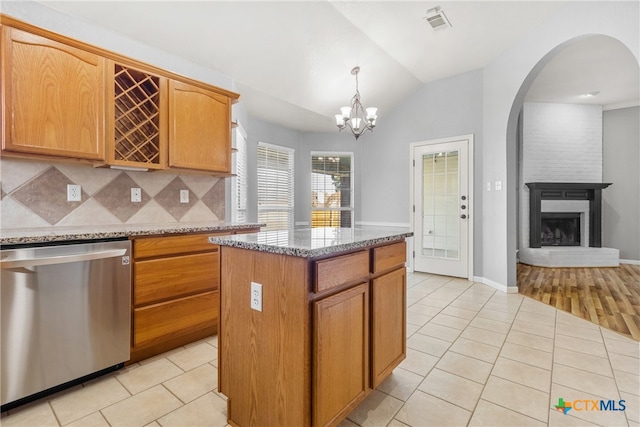 kitchen featuring a brick fireplace, vaulted ceiling, dishwasher, a center island, and hanging light fixtures