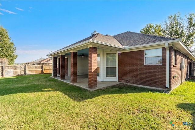 rear view of property featuring a lawn and a patio area