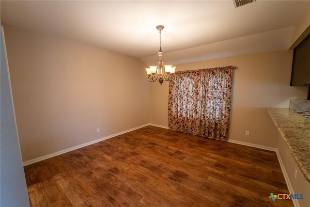 unfurnished dining area featuring a chandelier and dark hardwood / wood-style floors