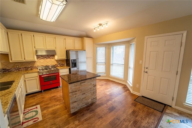 kitchen featuring light stone countertops, stainless steel appliances, tasteful backsplash, hardwood / wood-style floors, and a kitchen island