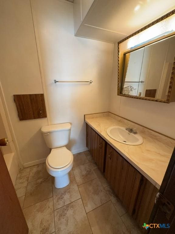 bathroom with vanity, toilet, and baseboards