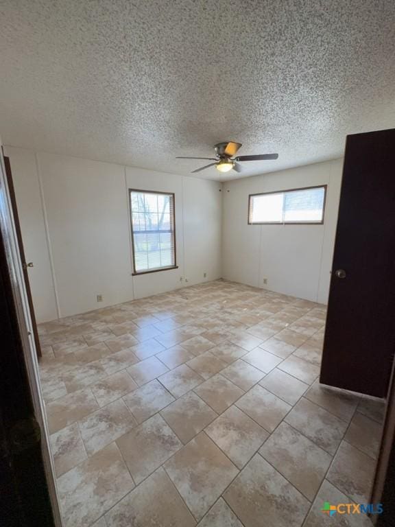 empty room featuring a textured ceiling and a ceiling fan