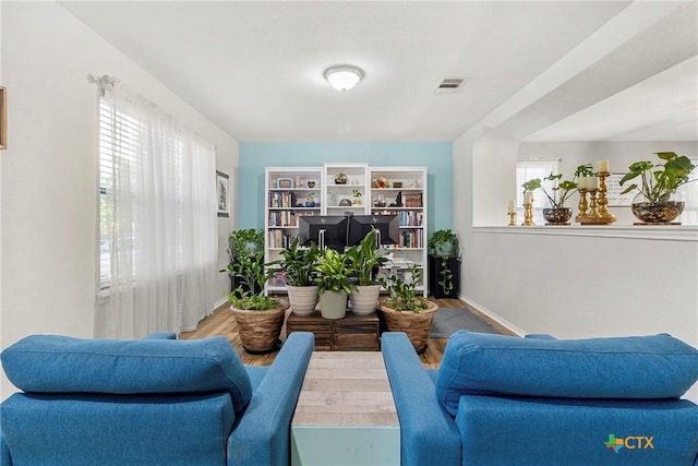 living area featuring wood finished floors, visible vents, and baseboards