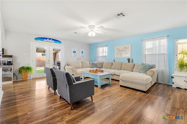 living area featuring a wealth of natural light, visible vents, wood finished floors, and ceiling fan