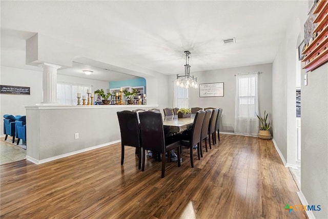 dining room with visible vents, baseboards, wood finished floors, and ornate columns