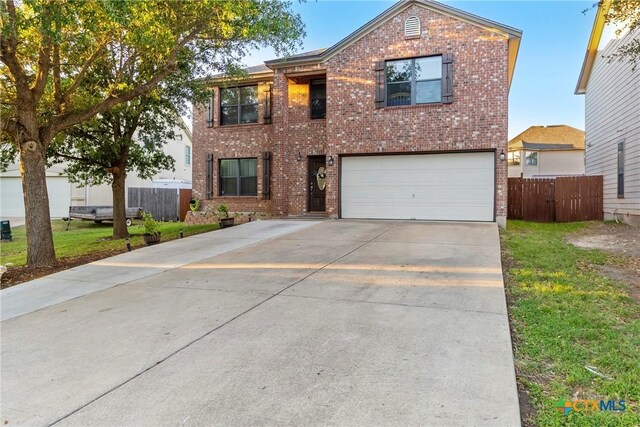 traditional home with a front yard, a garage, brick siding, concrete driveway, and fence