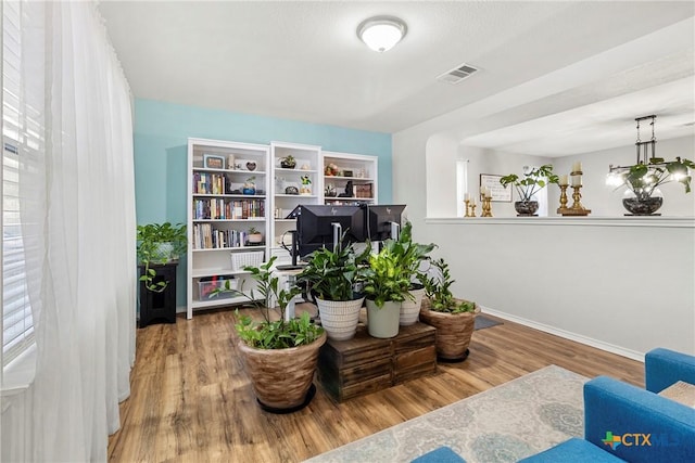sitting room with baseboards, visible vents, and wood finished floors