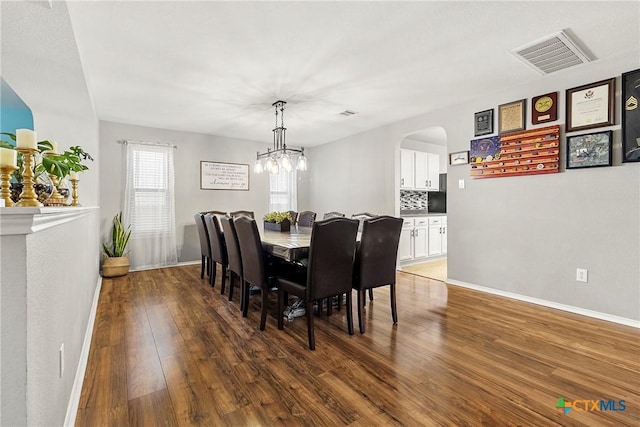 dining area with arched walkways, visible vents, wood finished floors, and baseboards
