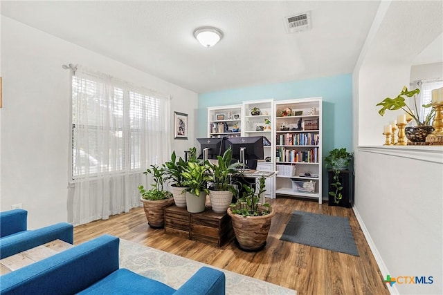 living area featuring baseboards, visible vents, and wood finished floors