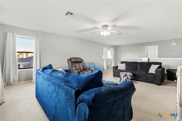 living room with visible vents, a ceiling fan, and light carpet