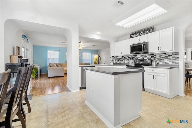 kitchen featuring stainless steel appliances, tasteful backsplash, visible vents, white cabinetry, and arched walkways