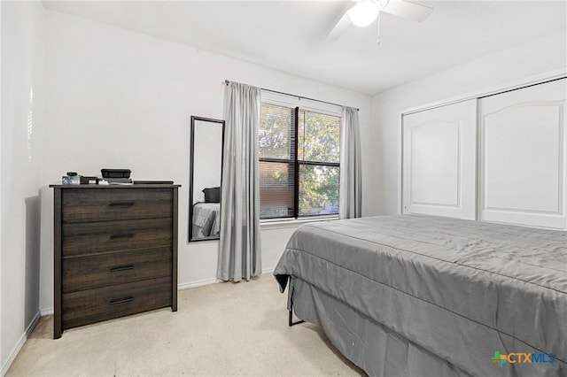 bedroom with a ceiling fan, a closet, light carpet, and baseboards