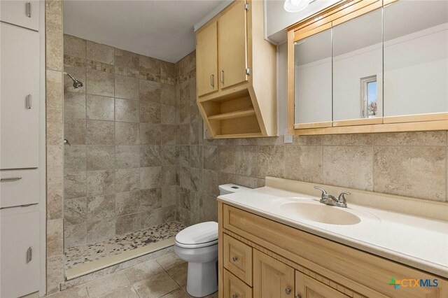 bathroom with toilet, tile patterned flooring, vanity, a shower stall, and tile walls