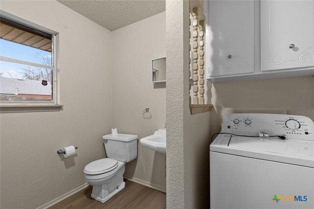 bathroom featuring toilet, a textured ceiling, wood finished floors, washer / dryer, and baseboards