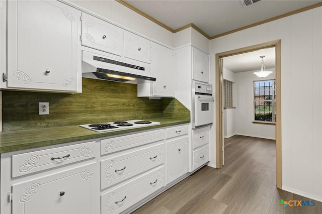 kitchen featuring dark wood-style flooring, dark countertops, white cabinets, white appliances, and under cabinet range hood