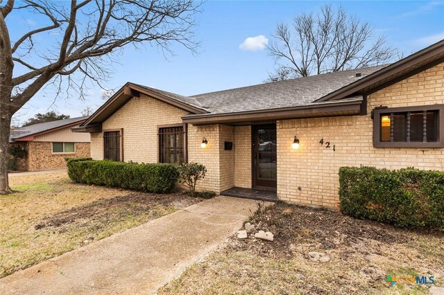 ranch-style house with brick siding and roof with shingles