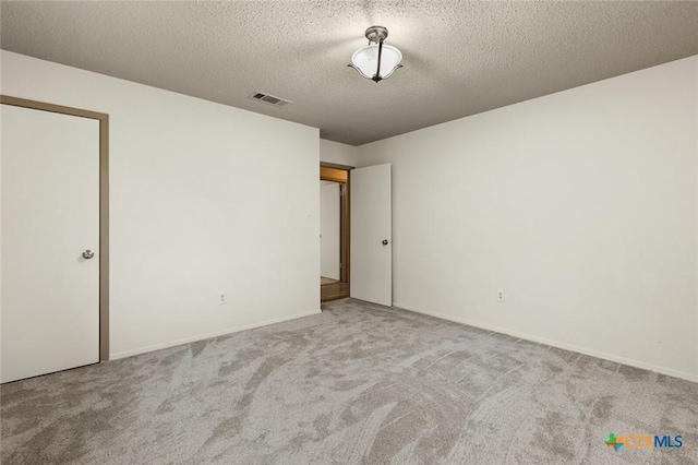 unfurnished room with a textured ceiling, carpet floors, and visible vents