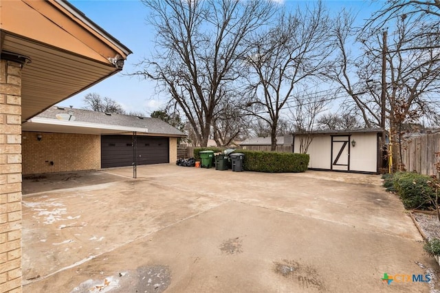 exterior space featuring a garage, fence, concrete driveway, and an outdoor structure