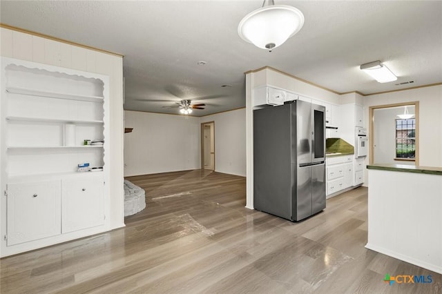 kitchen with visible vents, light wood-style flooring, white oven, freestanding refrigerator, and white cabinetry