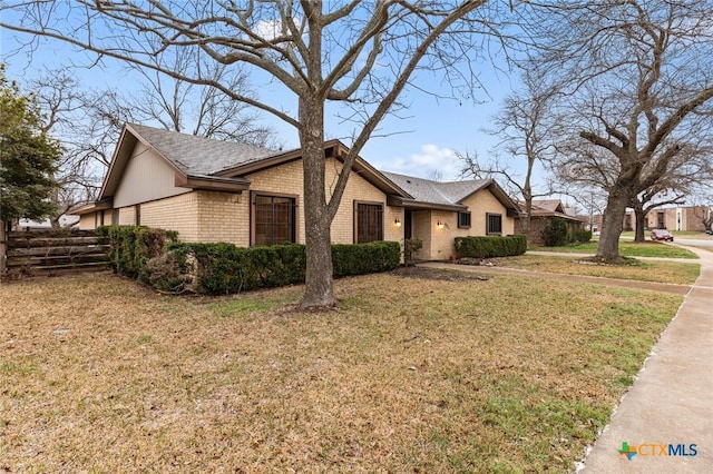 single story home with brick siding, fence, and a front lawn