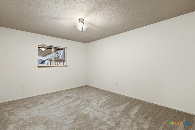 spare room with a textured ceiling, carpet floors, and baseboards