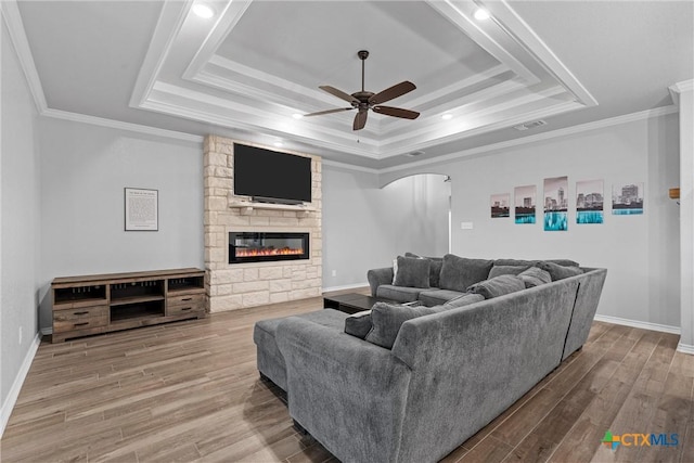 730 Eagle Pass Dr, Salado, TX 76571 - living room with a raised ceiling, wood-type flooring, a stone fireplace, and ornamental molding