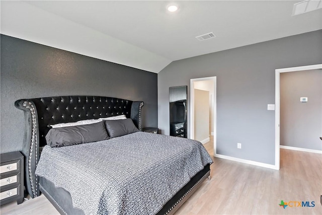 bedroom with lofted ceiling, visible vents, wood finished floors, and baseboards