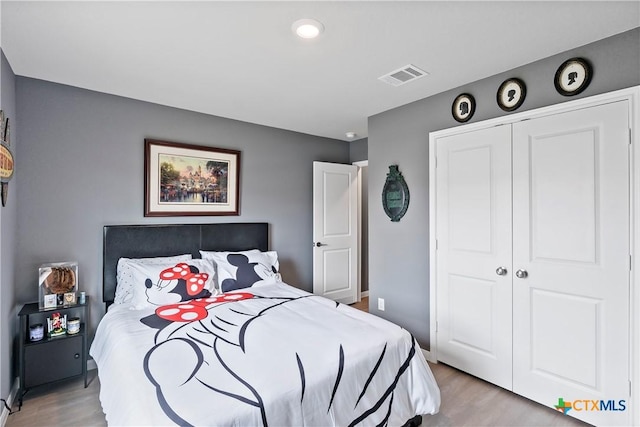 bedroom featuring visible vents, baseboards, light wood-style flooring, and a closet