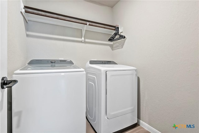 washroom featuring separate washer and dryer, laundry area, and a textured wall