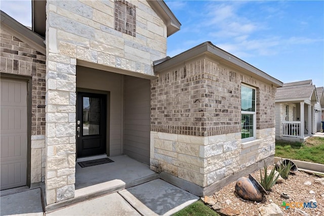 doorway to property featuring a garage and stone siding
