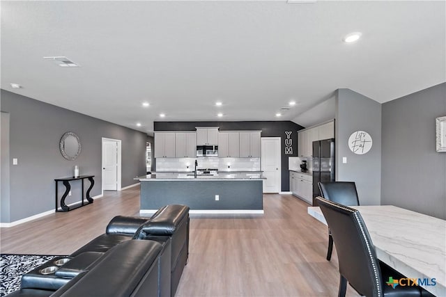 living area with recessed lighting, visible vents, light wood-style flooring, baseboards, and lofted ceiling