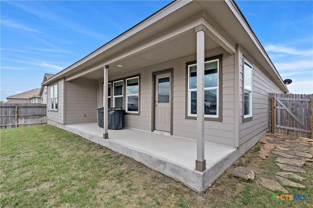 rear view of property featuring fence, a patio area, and a yard