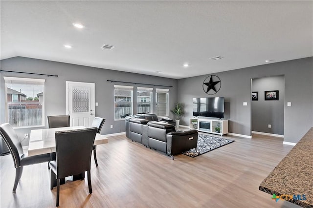 living area with baseboards, visible vents, a wealth of natural light, and light wood-style flooring