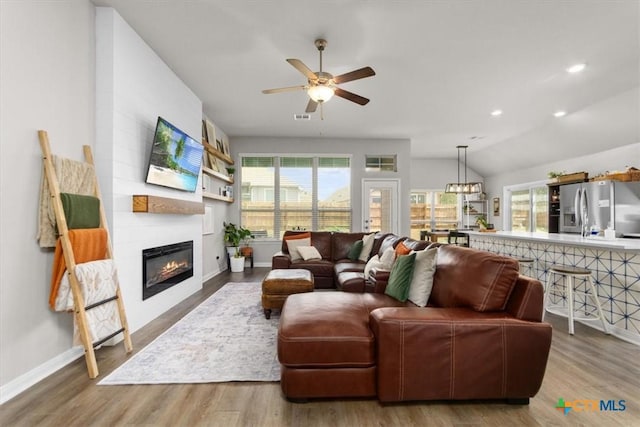 living room featuring a fireplace, wood-type flooring, ceiling fan, and vaulted ceiling