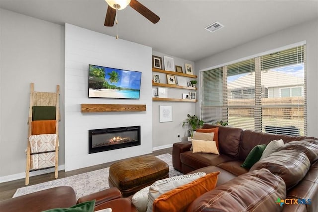 living room with hardwood / wood-style flooring, ceiling fan, and a fireplace