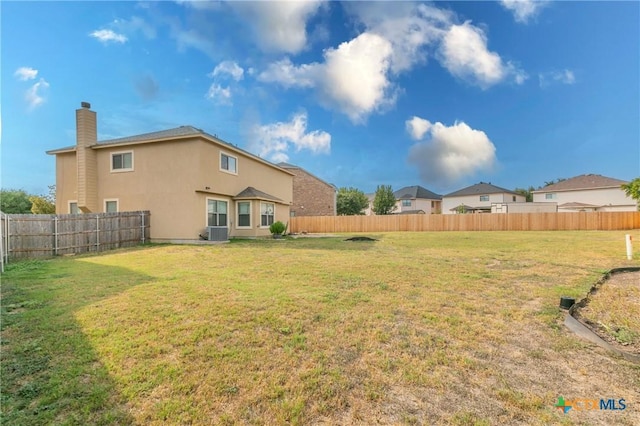 rear view of property featuring central AC and a lawn