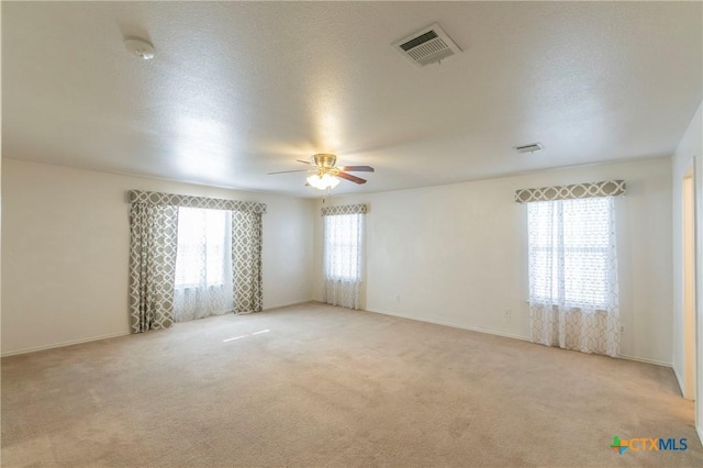 unfurnished room featuring ceiling fan, light carpet, and a textured ceiling