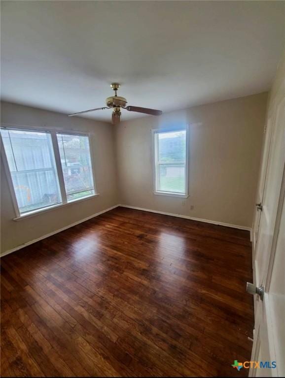 empty room featuring dark wood-style flooring, baseboards, and ceiling fan