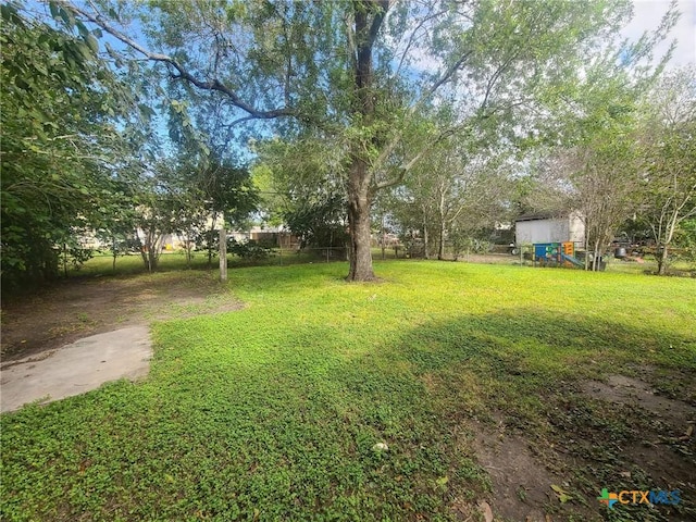 view of yard featuring fence, an outbuilding, and a storage unit