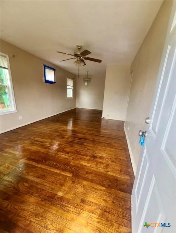 unfurnished room with baseboards, a ceiling fan, and wood finished floors