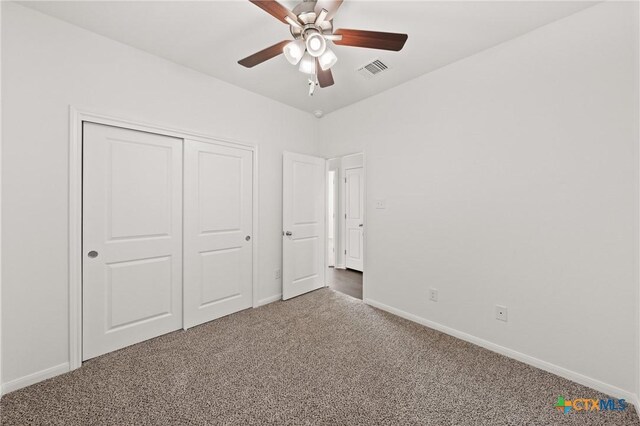 unfurnished bedroom featuring carpet floors, a closet, visible vents, a ceiling fan, and baseboards