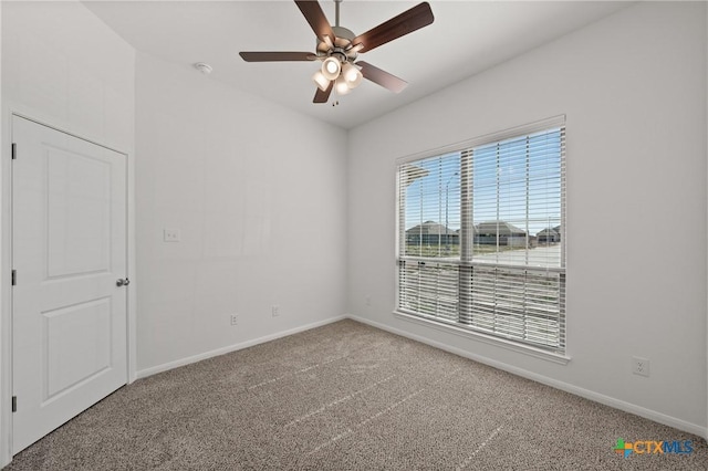 carpeted spare room with a ceiling fan and baseboards