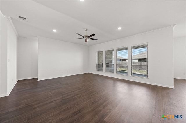 empty room featuring dark wood-style floors, visible vents, crown molding, and a ceiling fan