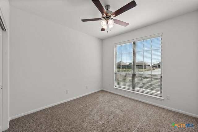 unfurnished room with carpet, a ceiling fan, and baseboards