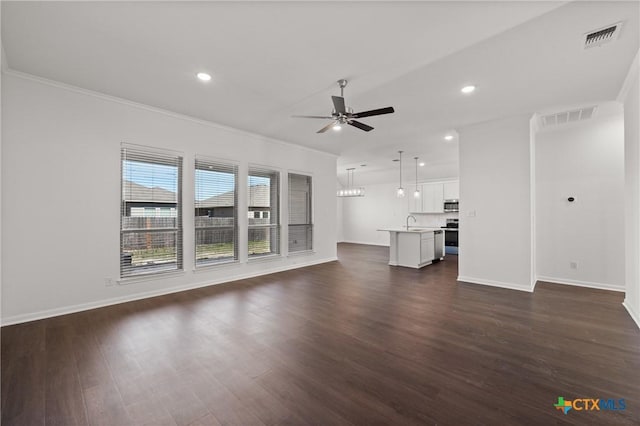 unfurnished living room with dark wood-type flooring, visible vents, ceiling fan, and a sink