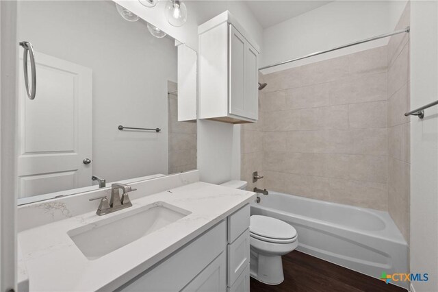 full bath with toilet, vanity, wood finished floors, and shower / bathtub combination