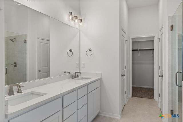 full bathroom featuring double vanity, a stall shower, and a sink