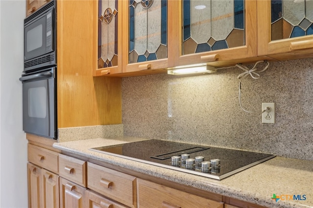 kitchen featuring light stone countertops, tasteful backsplash, and black appliances