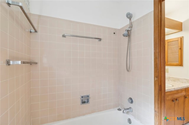 bathroom with tiled shower / bath combo and vanity